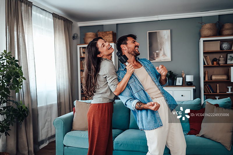 年轻情侣在家唱歌和享受乐趣图片素材