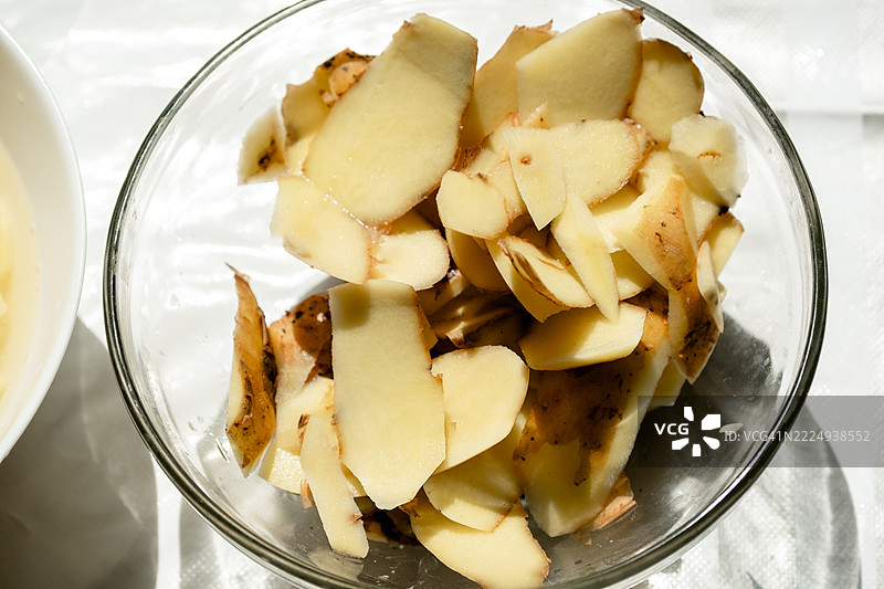 剥皮后的土豆皮放在桌子上的碗里图片素材
