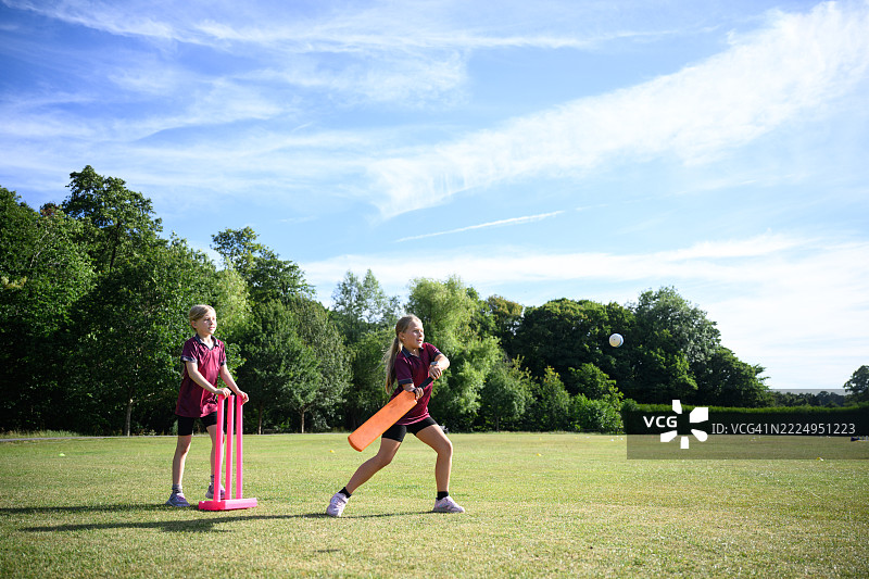 侧面视角的年轻女孩手持板球棒准备击球图片素材