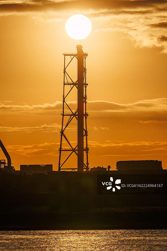 第一缕阳光升起，照耀着运河对岸的烟囱和电厂、钢铁厂的工厂。图片素材