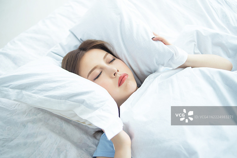 一位安静的女性在白色床上舒适地睡觉图片素材