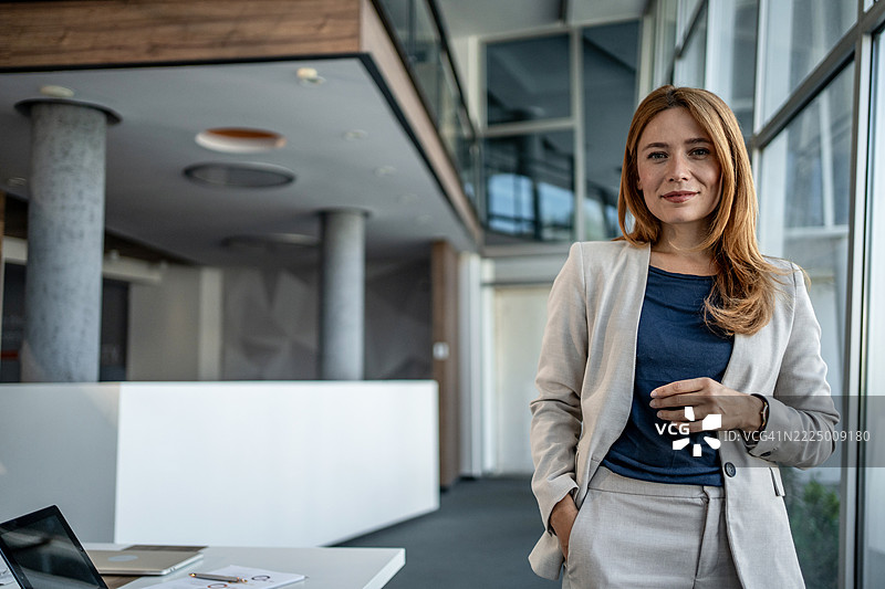 自信的女商人在现代办公大楼中微笑图片素材