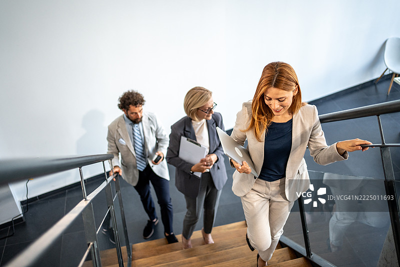 商务人士在现代办公室的楼梯上走下。图片素材