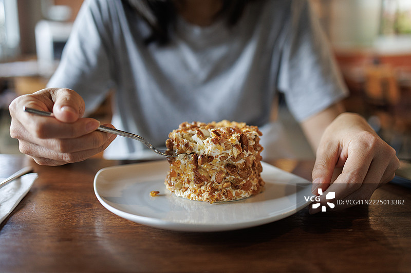 女人享用一块坚果裹的蛋糕图片素材