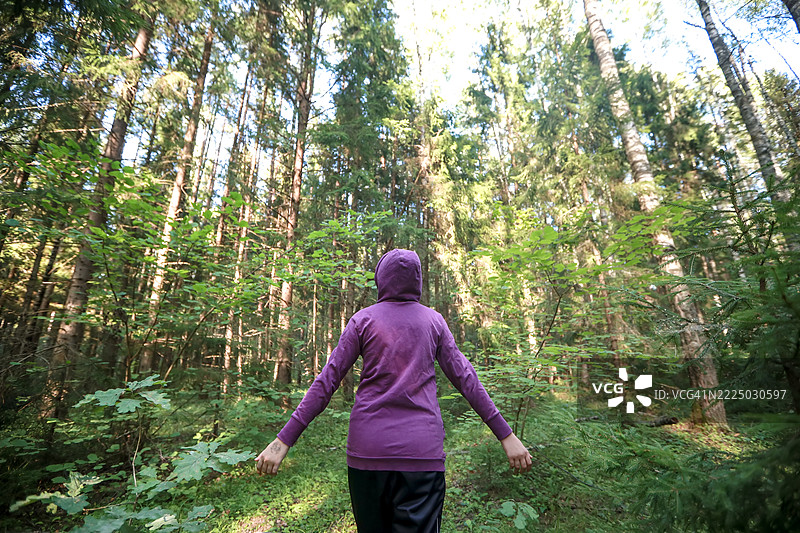 森林浴：穿着连帽衫的女孩张开双臂，深吸新鲜空气图片素材