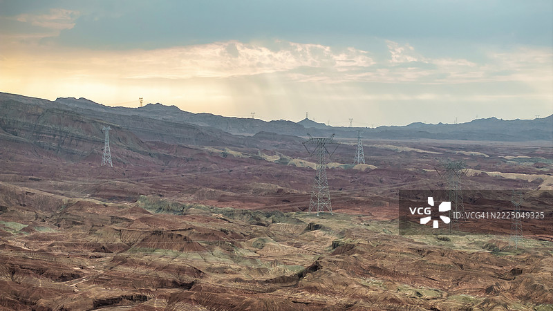 五彩斑斓的丹霞山脉与广袤的甘肃沙漠中的电力线相遇。图片素材