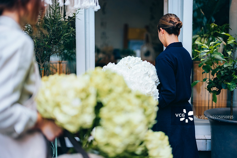 花店老板在迷人的户外花园店前整理花束图片素材
