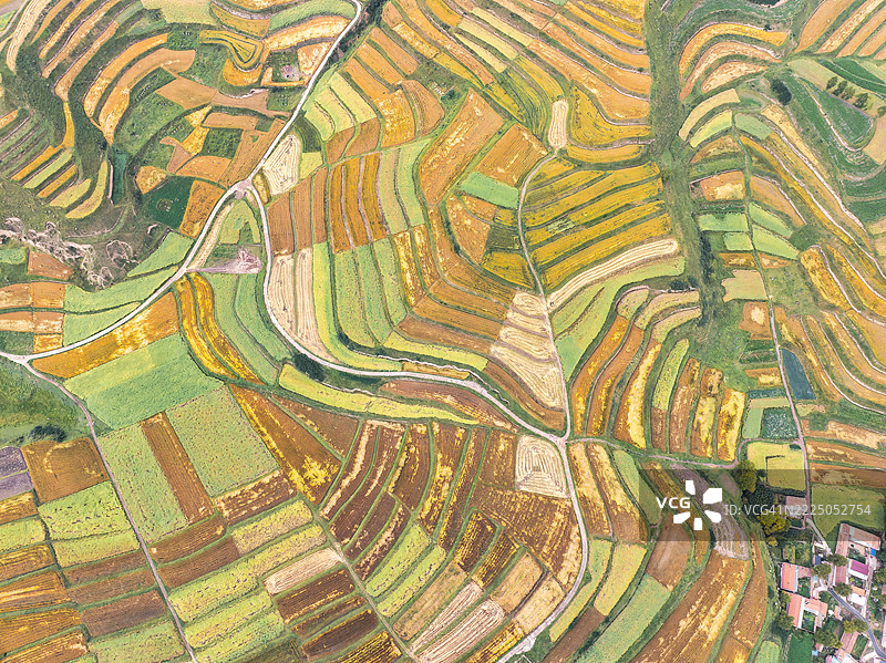 青海风景如画的山谷中，五彩斑斓的农田和蜿蜒的高速公路航拍图。图片素材