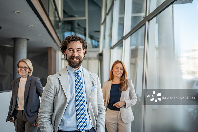 微笑的商务团队站在现代办公室走廊里图片素材