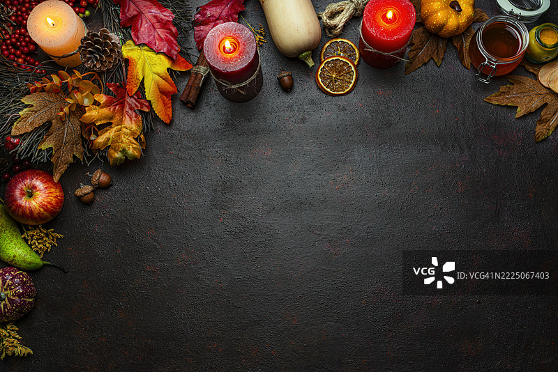 秋季或感恩节边框。装饰有燃烧的蜡烛、落叶、坚果、肉桂棒和南瓜。贺卡或留白空间。十月或季节。感恩节快乐图片素材