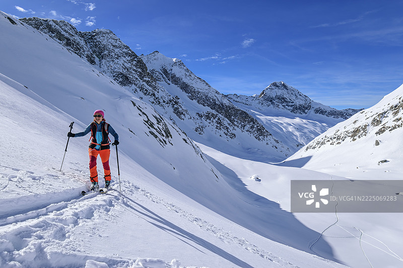 Mature woman with poles back country skiing towards Lenkjoechl on sunny day, Venediger Group, High Tauern, Ahrntal, South Tyrol, Italy图片素材