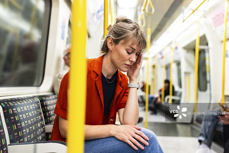 Tired woman touching head and sitting in train图片素材