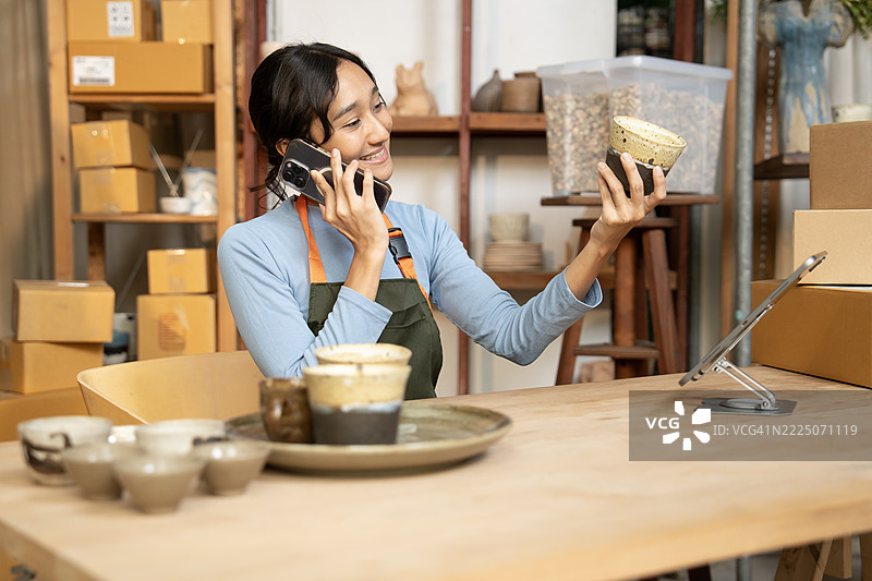 陶艺女性在小艺术工作室内打电话。图片素材