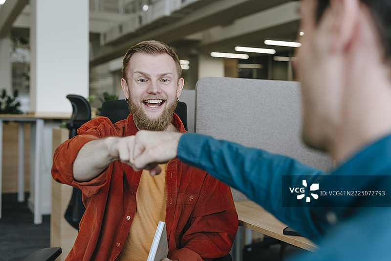 Colleagues sharing a fist bump in a coworking office图片素材