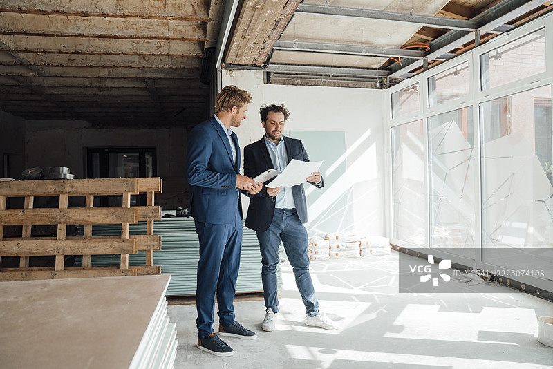Businessmen discussing construction plans at a construction site图片素材