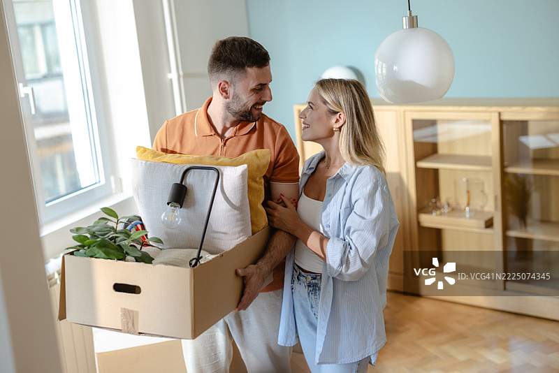 微笑的情侣一起搬入新公寓，搬运箱子图片素材