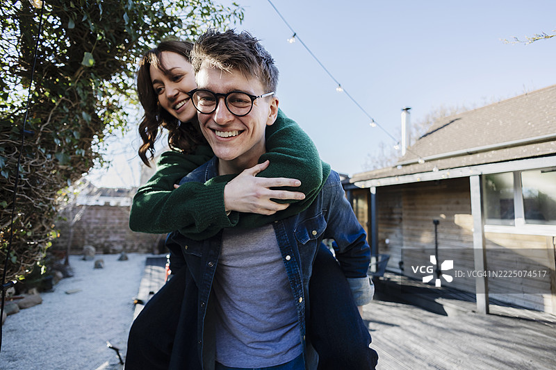 快乐的情侣在后院享受背负游戏图片素材