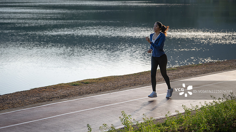 年轻的亚洲女性运动员在大自然中跑步。健康的女性在早晨慢跑。女性在户外公园锻炼。图片素材