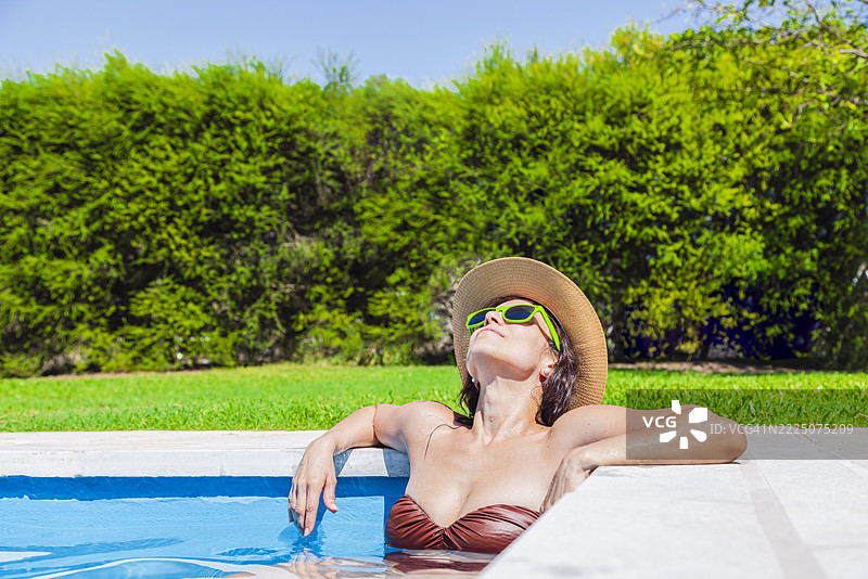 阿根廷夏季，一位女性在泳池旁晒太阳图片素材