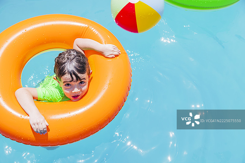 男孩在阿根廷的阳光明媚的日子里，玩着一个橙色的浮筒。图片素材