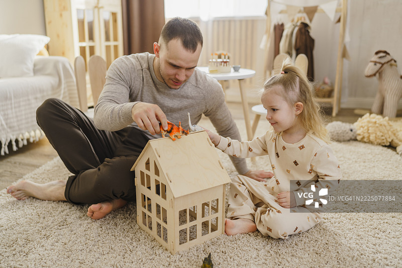 父亲和女儿在家中的儿童房间里玩玩具恐龙图片素材