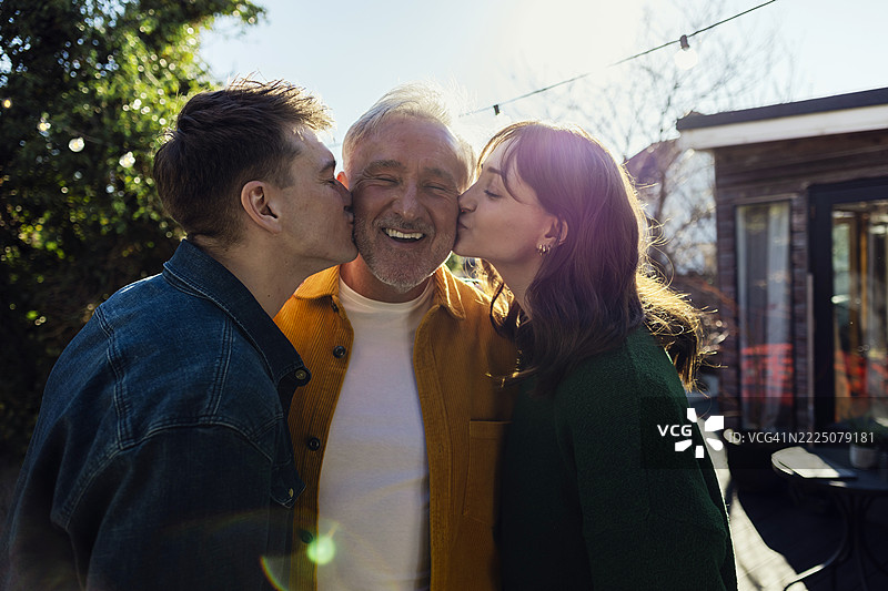 父亲在户外被儿子和女儿亲吻脸颊图片素材