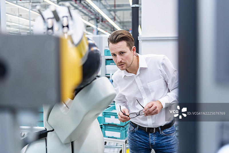 员工在生产大厅检查工业机器人图片素材
