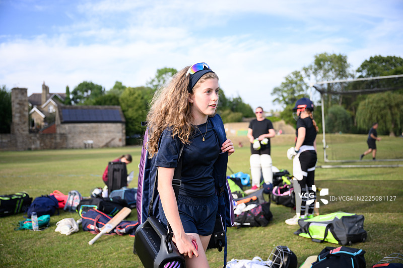 年轻女孩手提运动包，里面装有板球装备和音响，走进运动场准备练习的自然肖像。图片素材