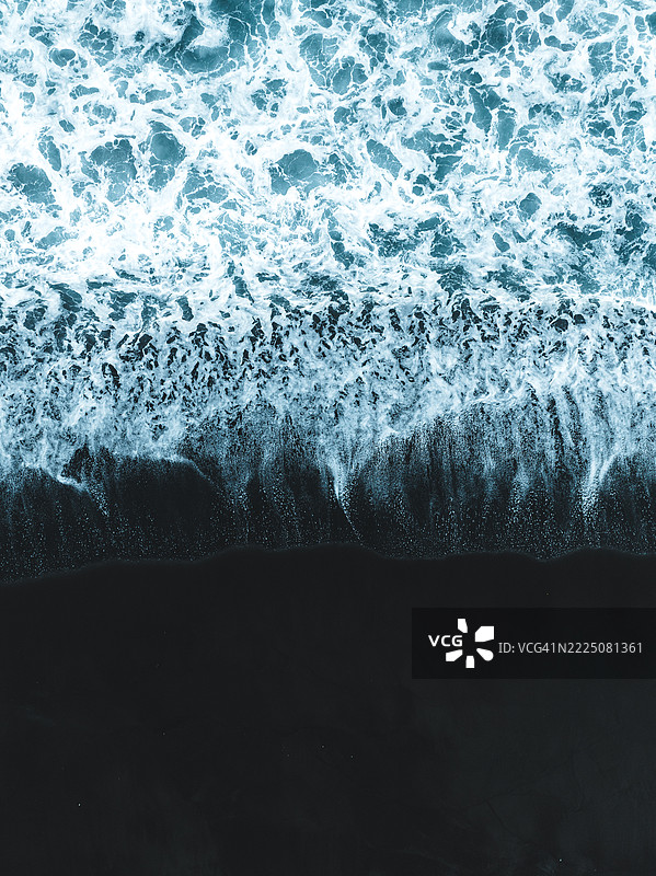 从无人机视角拍摄的巴厘岛克伦贡区黑沙滩上的海浪回流图片素材