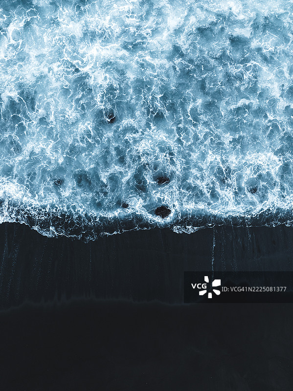 抽象无人机照片，展示了汹涌的海洋水域和黑沙滩，位于印度尼西亚巴厘岛克伦贡区。图片素材