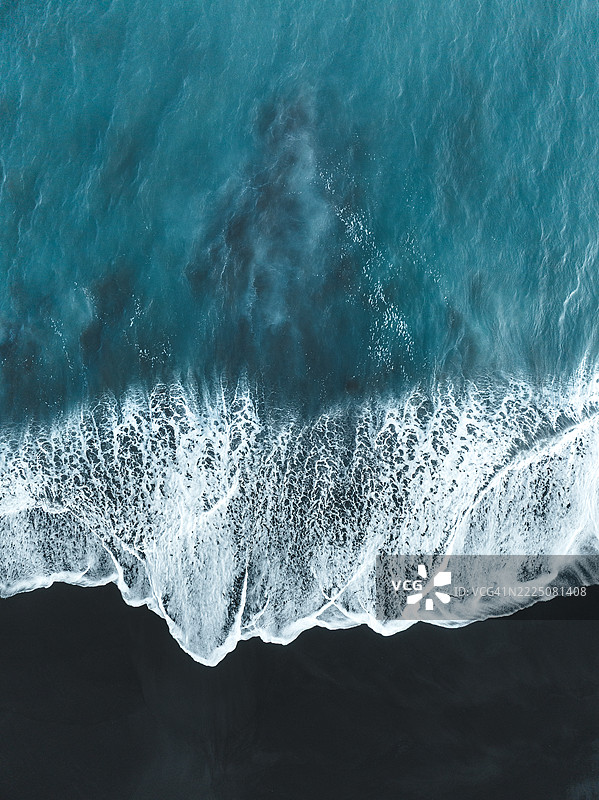 理想的无人机图像，展示印度洋的海浪冲刷到巴厘岛克伦贡区的火山沙滩上。图片素材