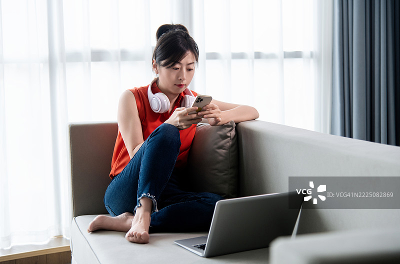 女人在沙发上使用手机和笔记本电脑图片素材