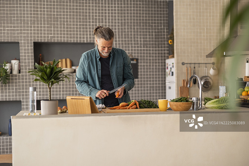 成熟男性在现代厨房中使用平板电脑烹饪图片素材