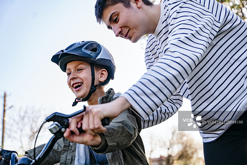 青少年在户外教弟弟骑自行车图片素材