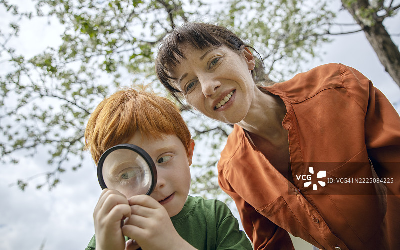 母亲和儿子在花园里用放大镜探索图片素材