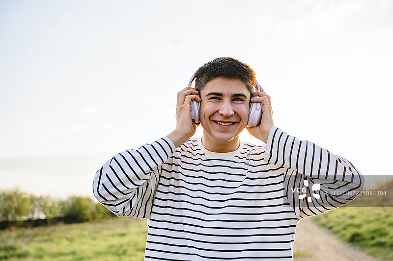 青少年在日落时分户外享受音乐，佩戴耳机图片素材