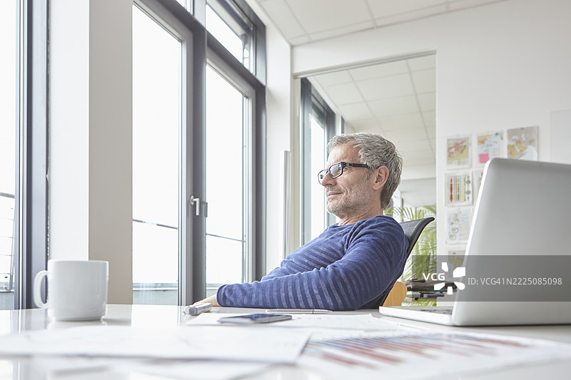 办公室里的商人乐观地望向窗外图片素材