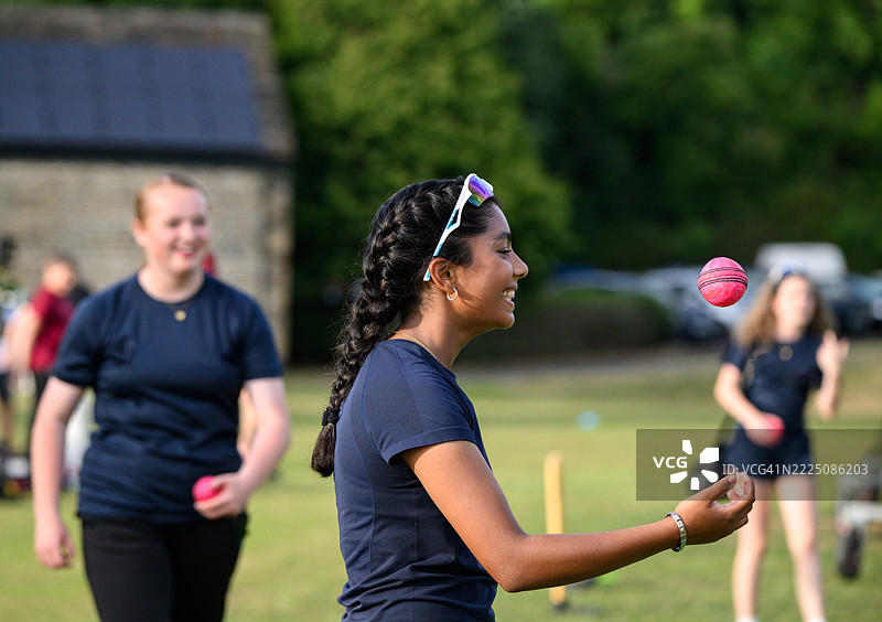 侧面视角的年轻女性在练习中投掷和接住板球图片素材