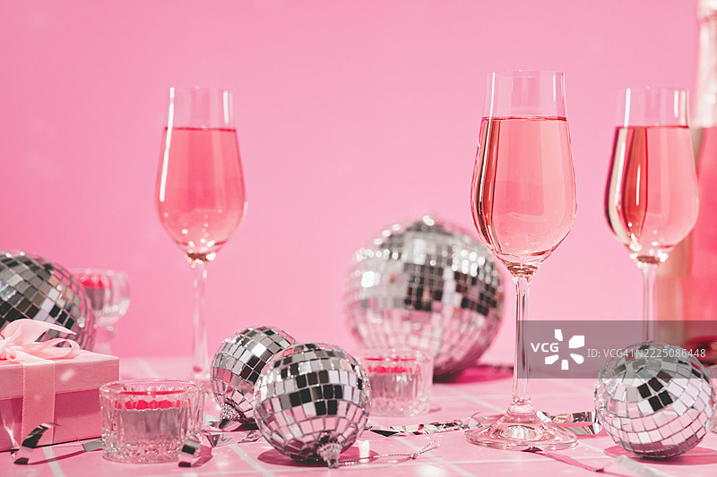 粉色派对桌上摆放着玫瑰色的起泡酒和迪斯科球的香槟杯图片素材