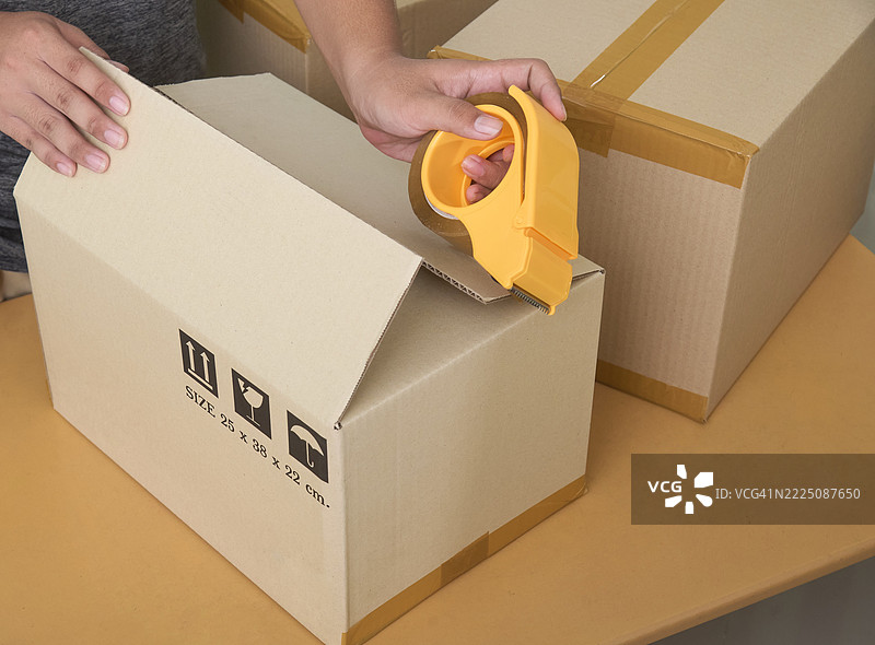 使用胶带分配器工具打包快递包裹图片素材