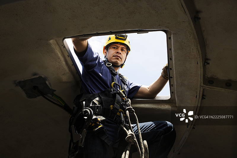 工程师从风力涡轮机的机舱中爬出进行维护检查图片素材