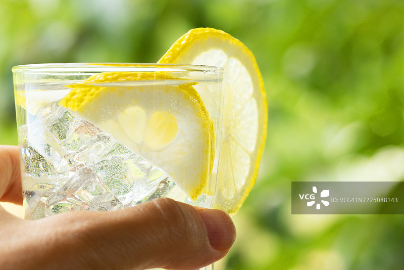 女人手中拿着清爽的柠檬水。夏季排毒饮品的概念。健康生活方式。图片素材