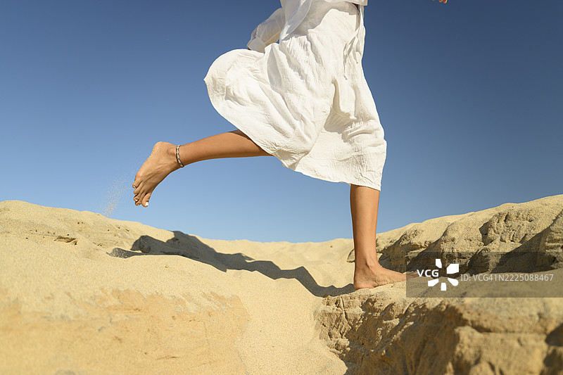 女人在沙漠环境中赤脚奔跑在沙子上图片素材
