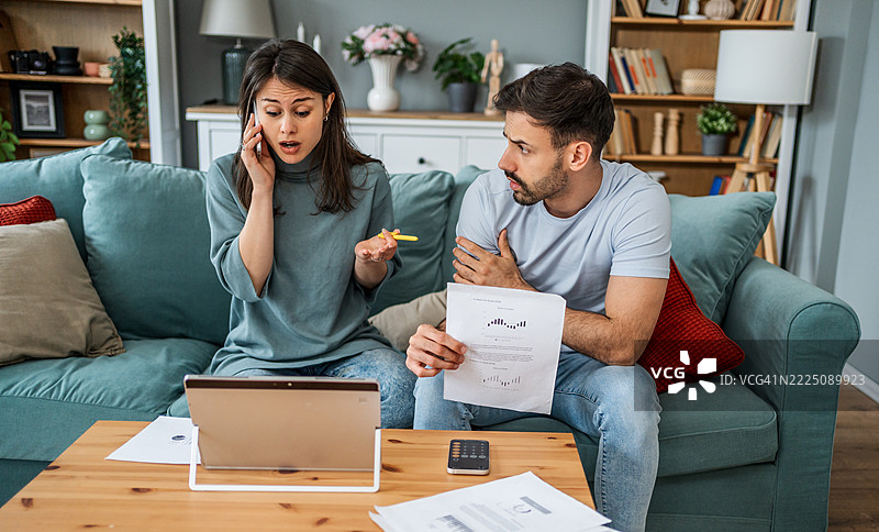 年轻夫妇在家查看文件时担心财务问题图片素材
