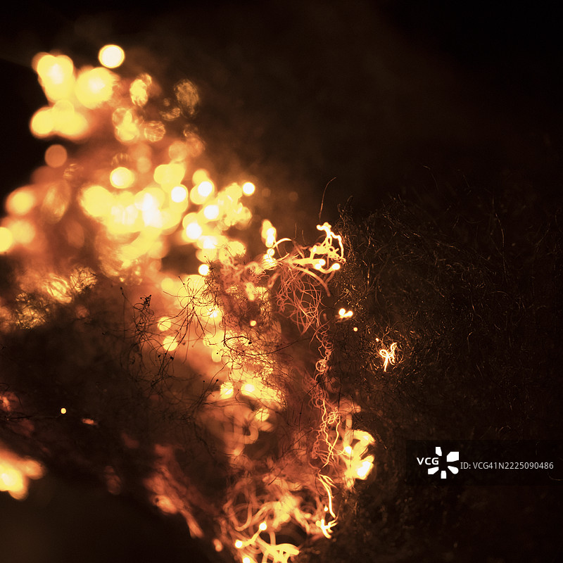 在黑暗中，钢丝绒被点燃时，明亮的火花四溅。图片素材