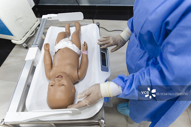 医学生在医院环境中使用婴儿玩偶进行医疗培训图片素材