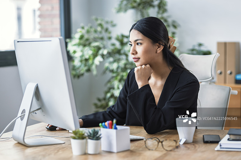 年轻女企业家在办公室桌前工作，旁边有电脑和咖啡图片素材