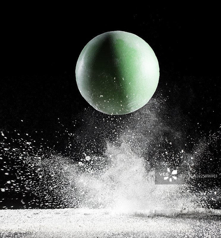 绿色球在黑色背景下与白色粉末表面碰撞和反弹的效果图片素材