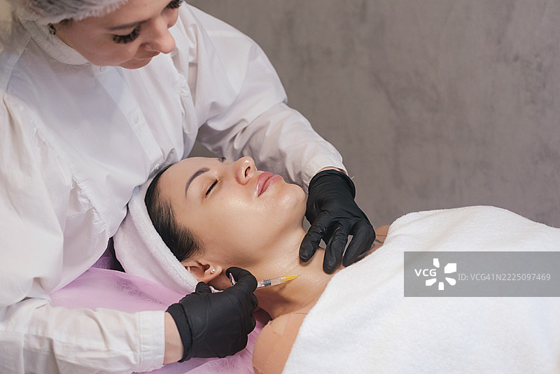中年女性在美容院接受面部注射图片素材