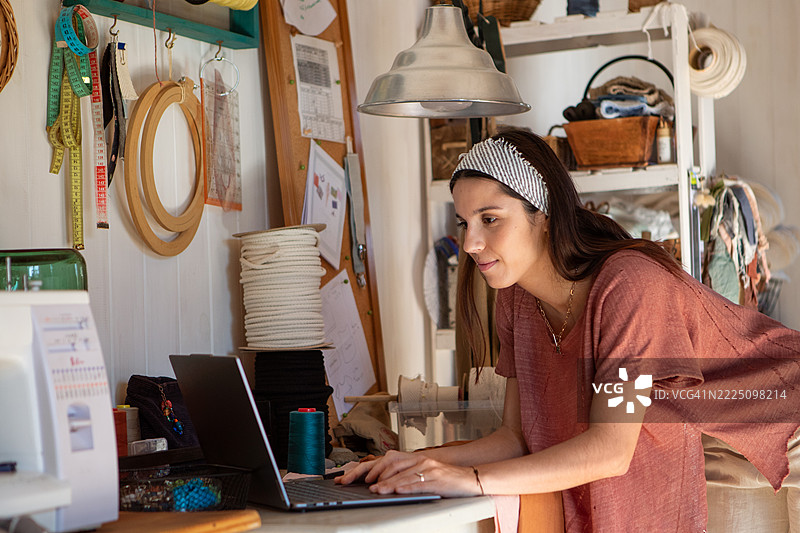 年轻女性纺织企业家在她的创意工作室里图片素材